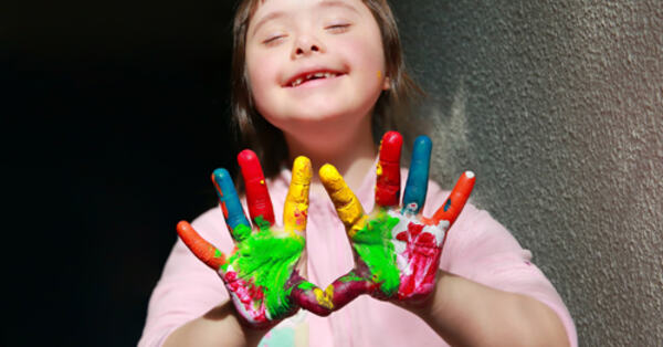 Bilde av glad jente med fargerik maling på fingrene
