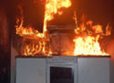 Brann på kjøkken. Kjøkkenbenk, komfyr og overskap i full brann. 