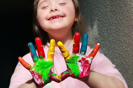 Bilde av en glad jente som holder sine åpne malte hender opp foran seg