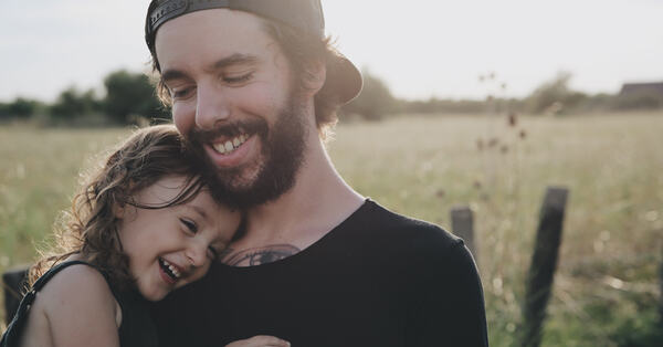 Bilde av en smilende mann som holder en leende jente på armen