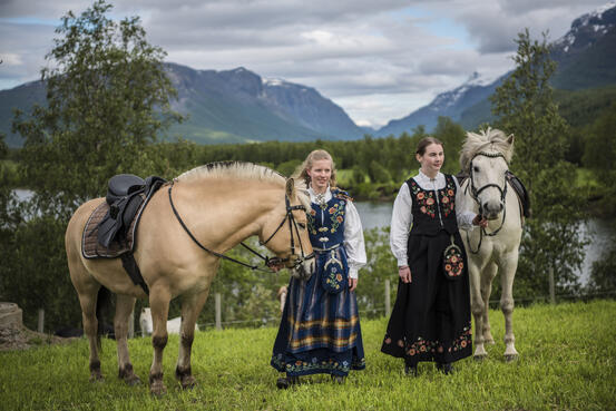 Jenter i bunad som holder hester ved Eggen gård.