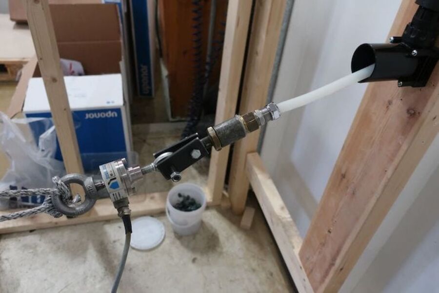 Testing av utskiftbarhet for rør-i-rør-system. En person trekker ut røret gjennom veggboksen for hånd, nødvendig uttrekkskraft registreres av kraftmåler. Foto: SINTEF Byggforsk