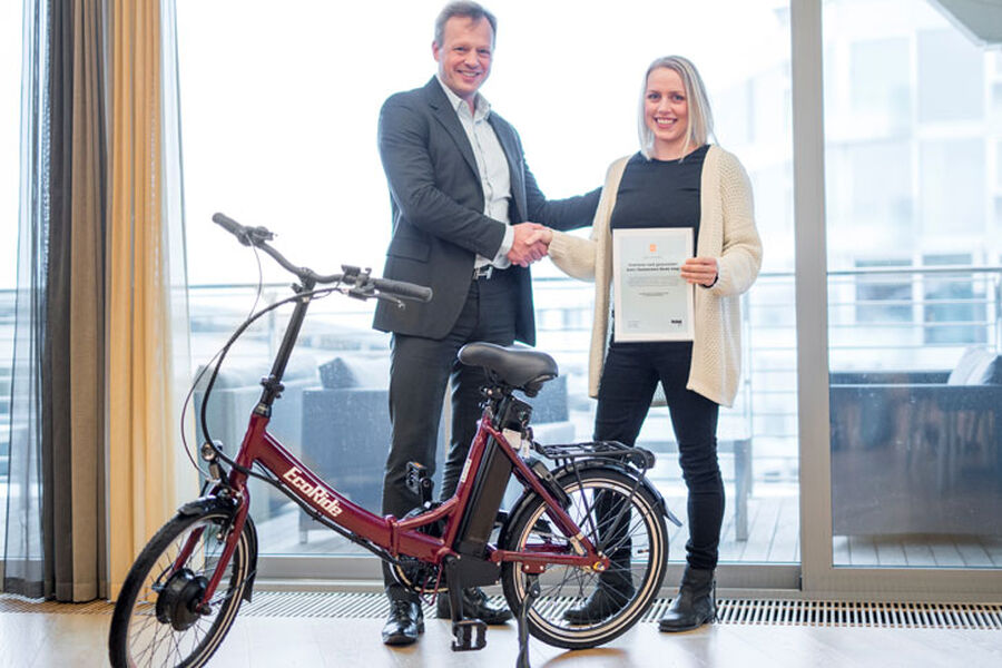 Stig Bech, nestleder for styret i Bygg21 og partner i advokatfirmaet BA-HR,  overleverer hovedpremien i julekalenderen, en Ecoride Flexible el-sykkel ». Vinneren var interiørarkitekten Ine Elisabeth Bangås, som var strålende fornøyd med julegaven fra Bygg21.