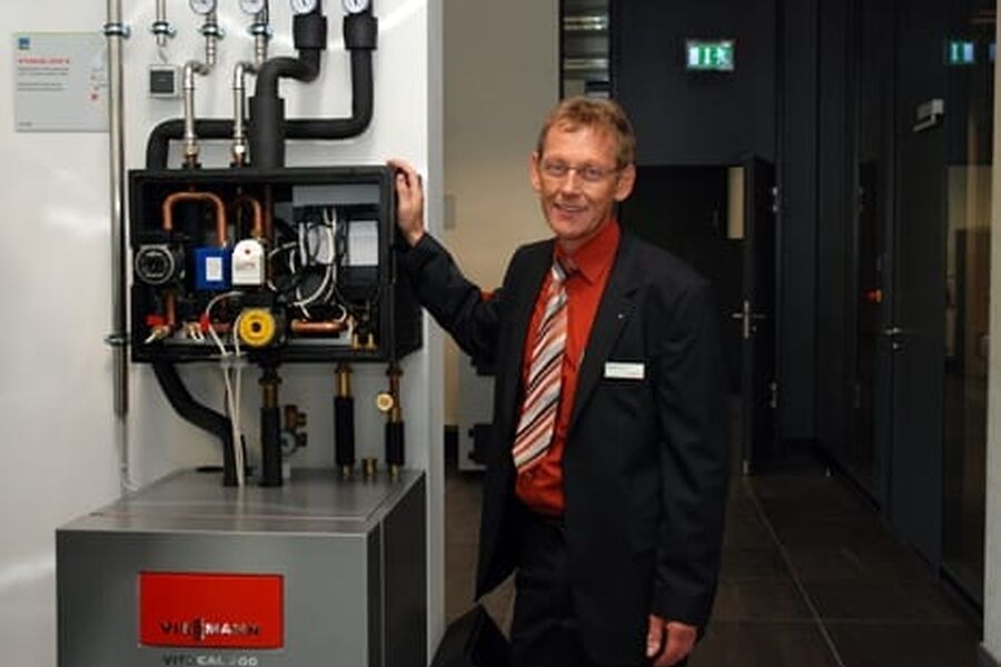 Manfred Asmuth med en varmepumpe som bruker gass til spisslasten. Foto: Ole Daniel Enersen