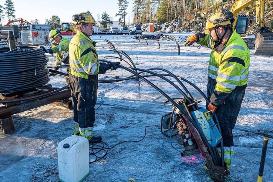 Brønnene er akkurat ferdig boret. Her settes kollektorene ned av Dani Nanne (ved slangeveilen), Tom Hamsund (i midten) og Shukrulla Iskaov ved kollektorsetteren på brønnen. Foto: Båsum Boring AS