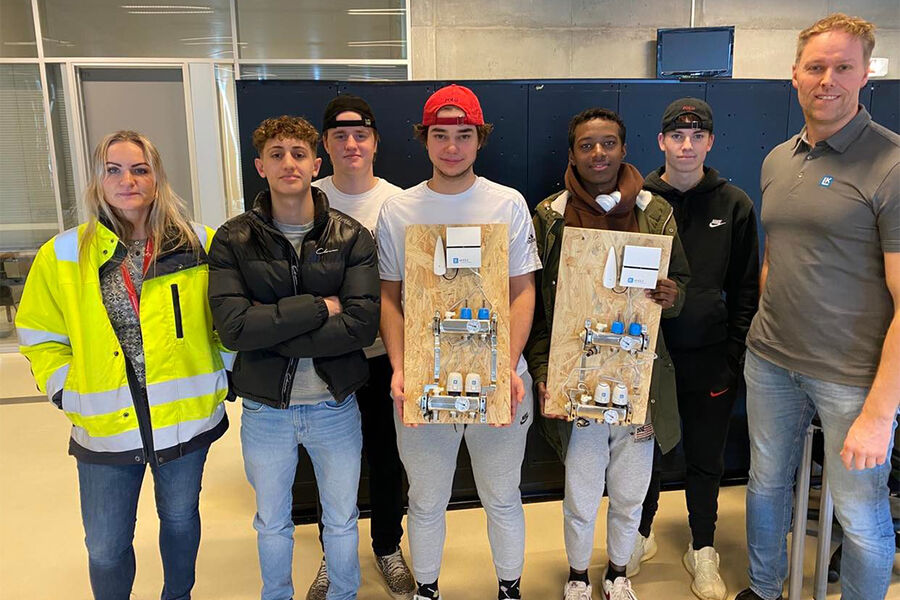 Et knippe fremtidige rørleggere viser frem læringsmateriell fra LK, avbildet sammen med kontaktlærer Hilde Horpestad og LKs Stanley Pettersen.