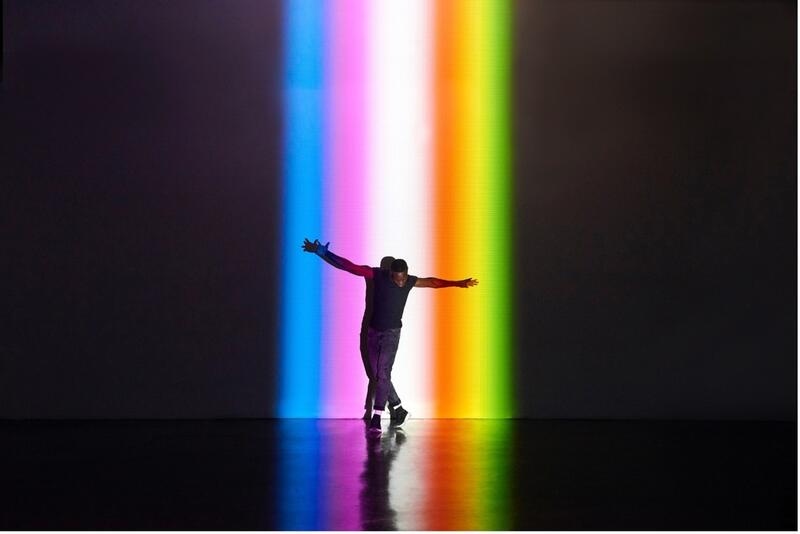 En som danser i regnbue-lyssetting