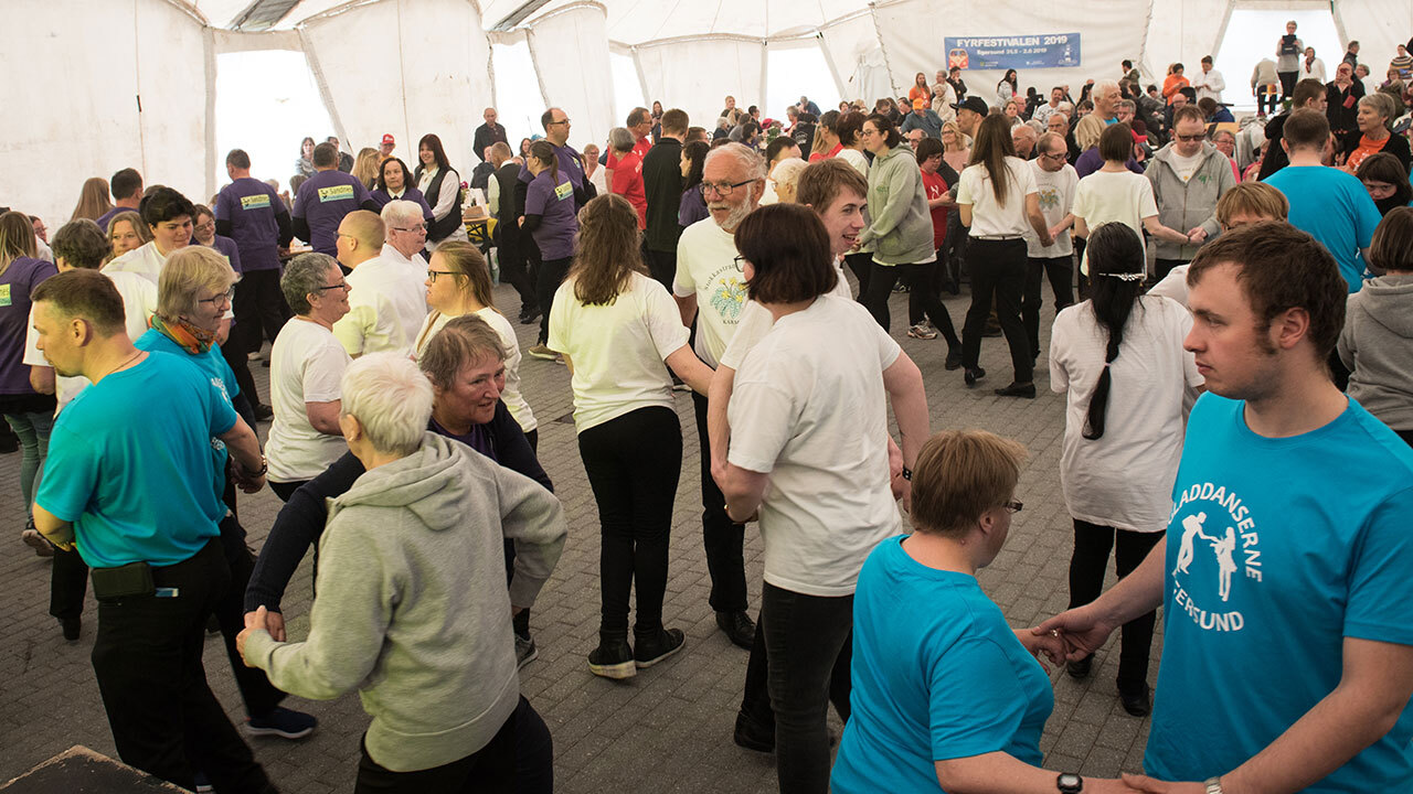 En stor gruppe mennesker som danser på dansegulvet