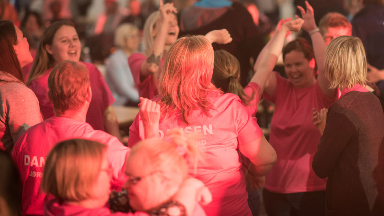 En gruppe med rosa t-sjorter som danser og smiler