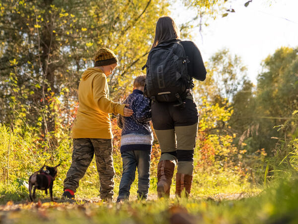 Familie som går tur i skogen om høsten