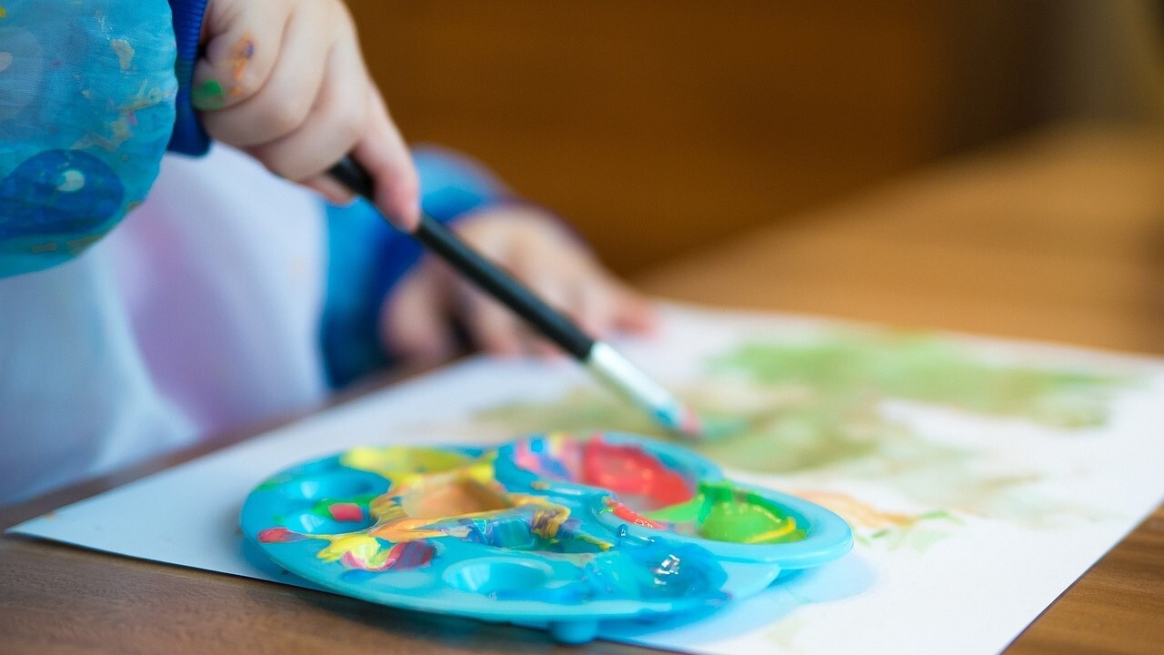 Barnehånd som maler med farger