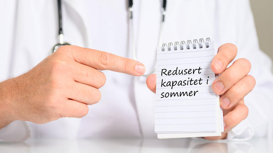 Lege som holder et skilt som sier at det er redusert kappasitet om sommeren