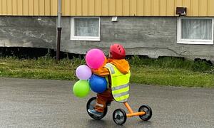 Barn med ballonger på trehjulssykkel