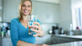 Ei dame på kjøkkenet som holder et glass med vann