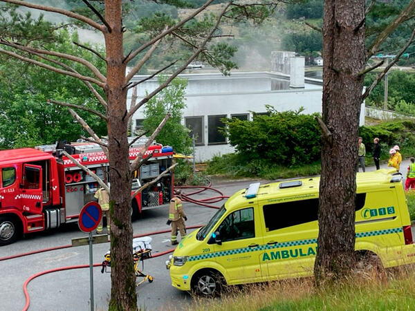 Brannbil og ambulanse utenfor bygget som brenner