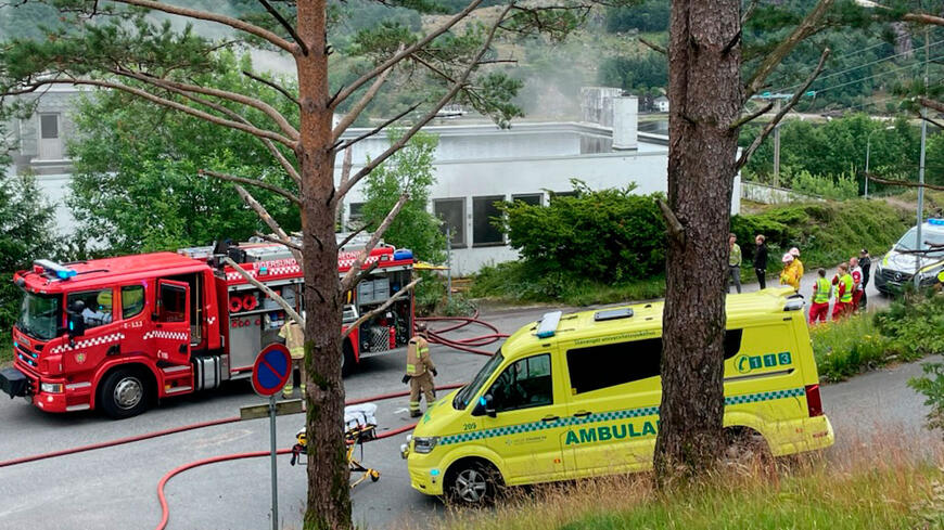 Brannbil og ambulanse utenfor bygget som brenner