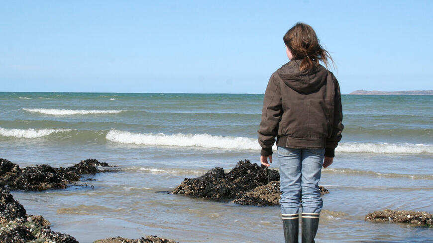 Dame på en strand som er ut over havet