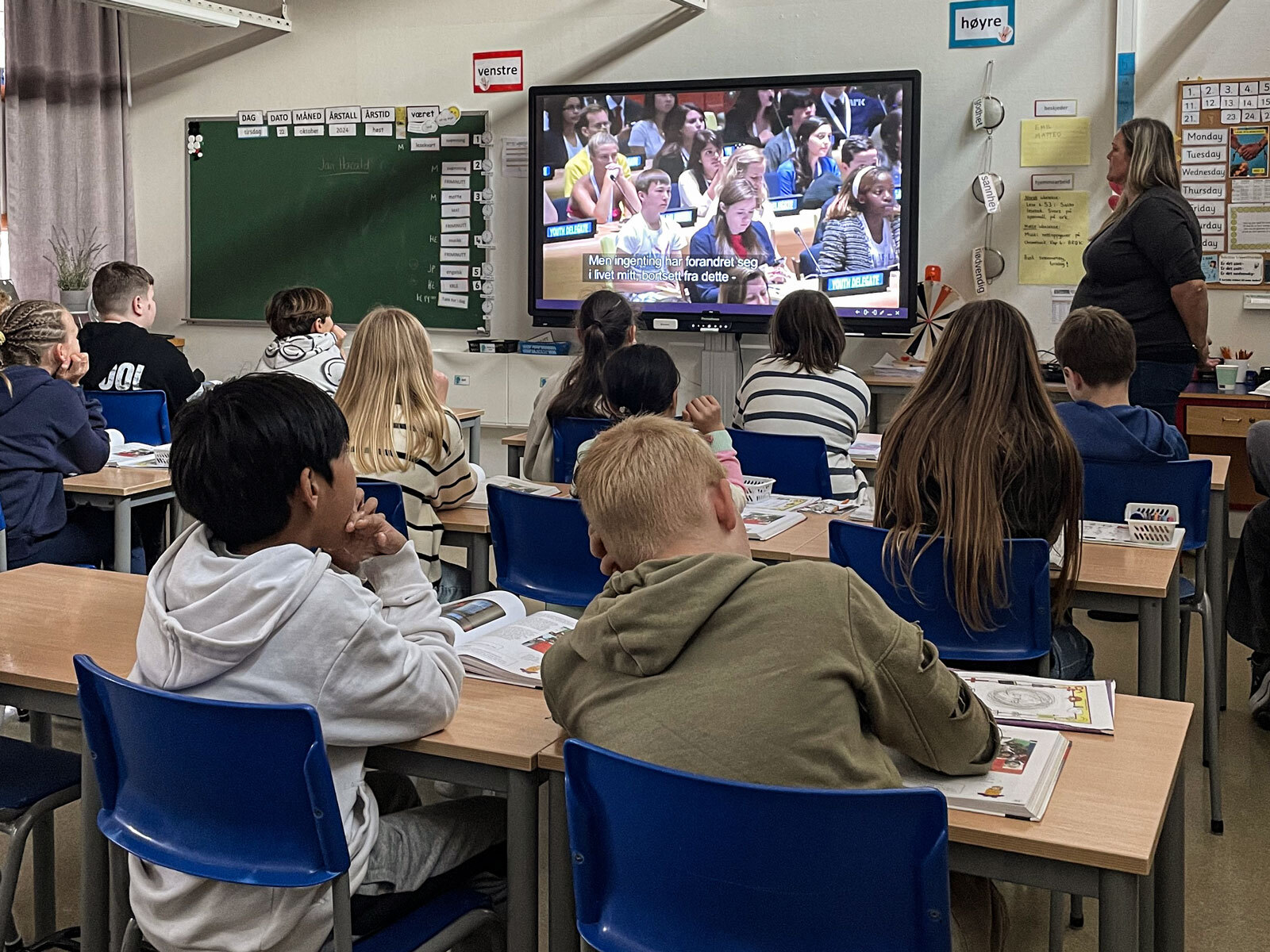 En skoleklasse som sitter i klasserommet og ser på nyhetene på en TV.
