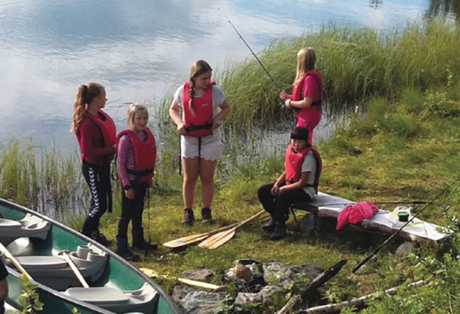 Barn ved fiskevann, kano og fiskestenger