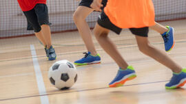 Barn som spiller fotball innendørs i en hall