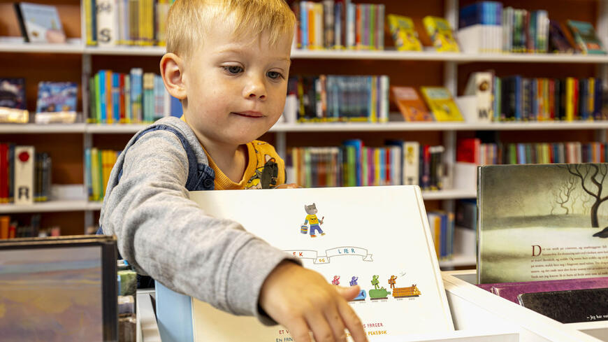 Barn på biblioteket som kikker i en bildebok