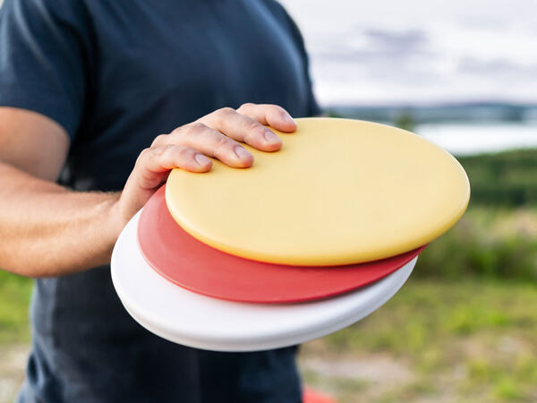 En person som holder tre sennebrett for frisbeegolf