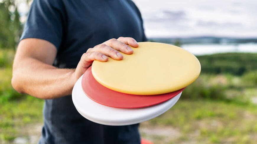 En person som holder tre sennebrett for frisbeegolf