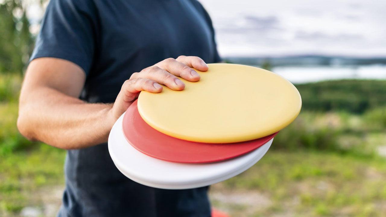 En person som holder tre sennebrett for frisbeegolf