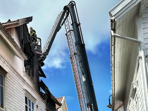 En brannmann i stigebil ved et hus som det har vært brann i