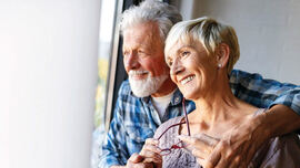 To pensjonister som smiler og ser ut av vinduet