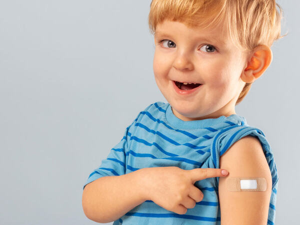 En liten gutt som har fått plaster på armen etter å ha tatt vaksine