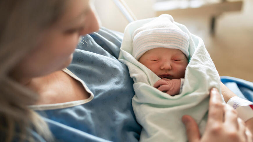 En nyfødt baby i fanget til mammaen