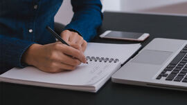 En person som noterer i en notatbok