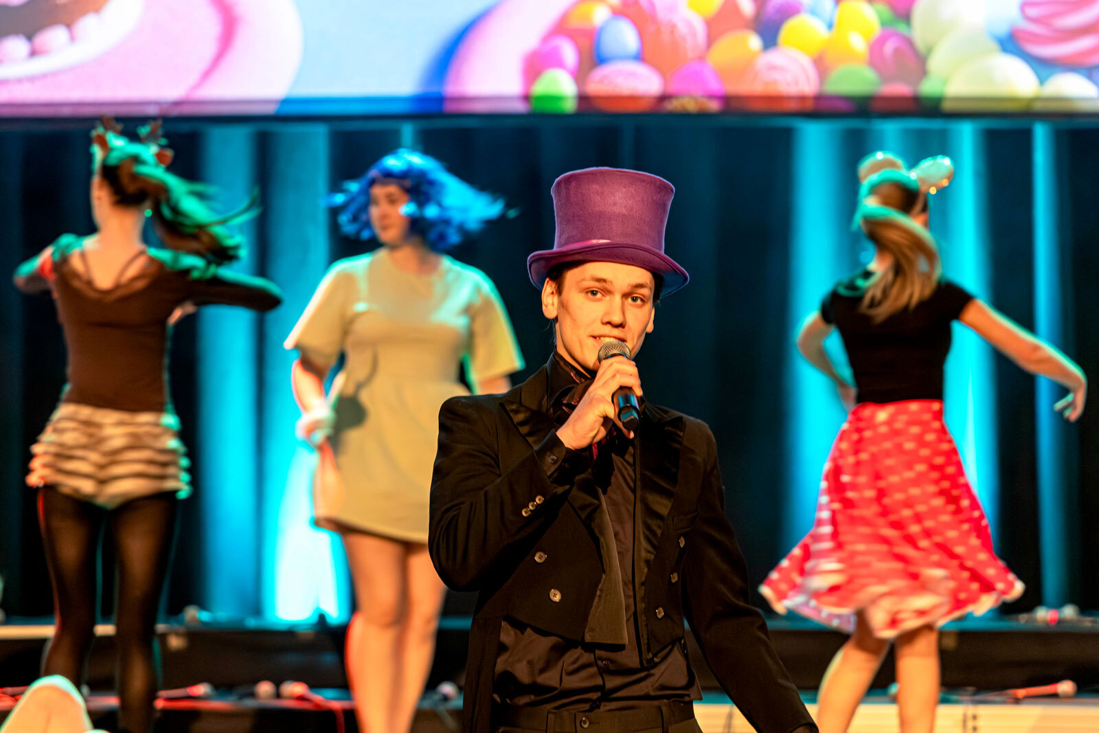 En elev som synger med dansere i bakgrunnen